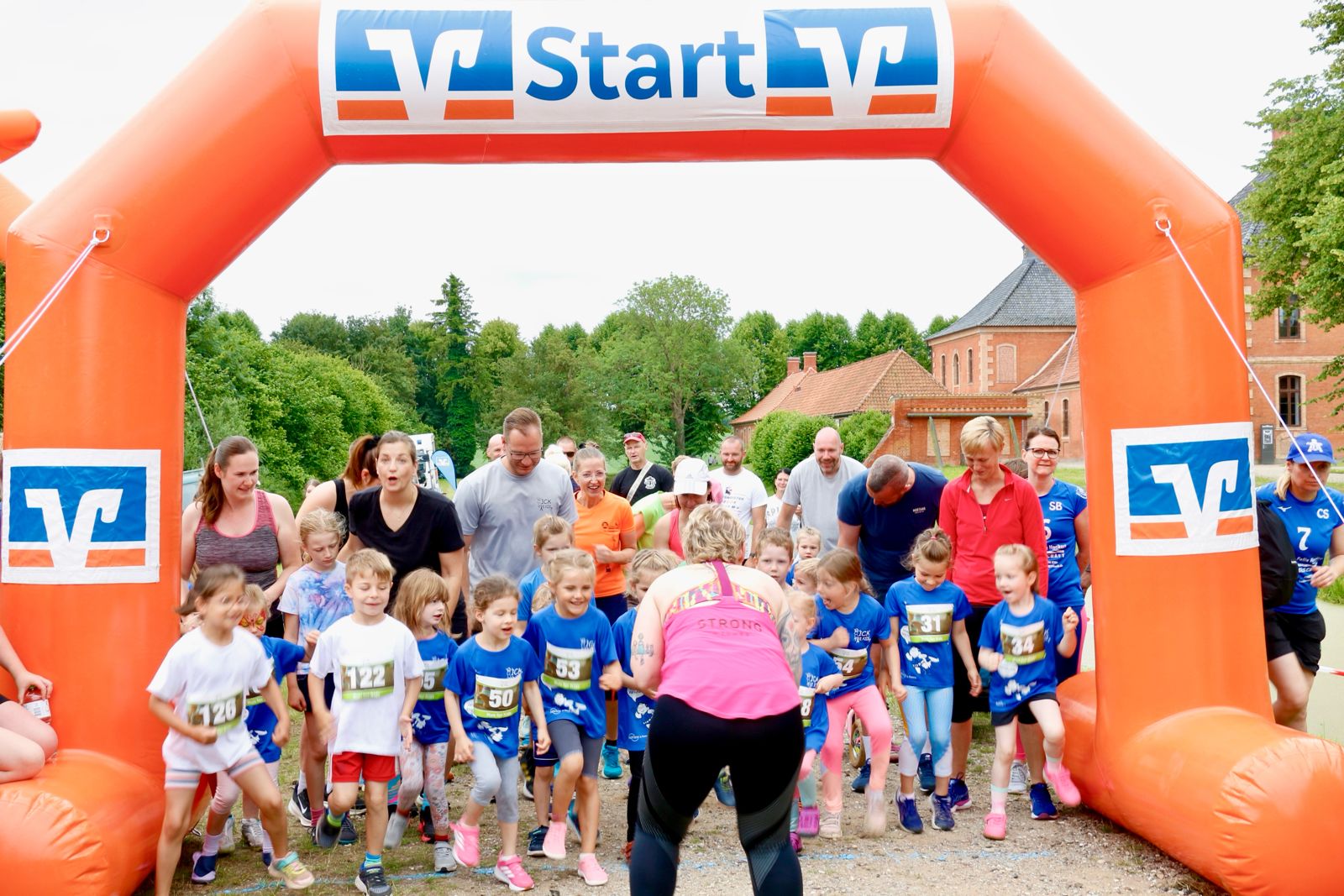Kinderlauf-Start unter dem Volksbankbogen am Schloss Bothmer – viele Kinder in blauen Trikots laufen los